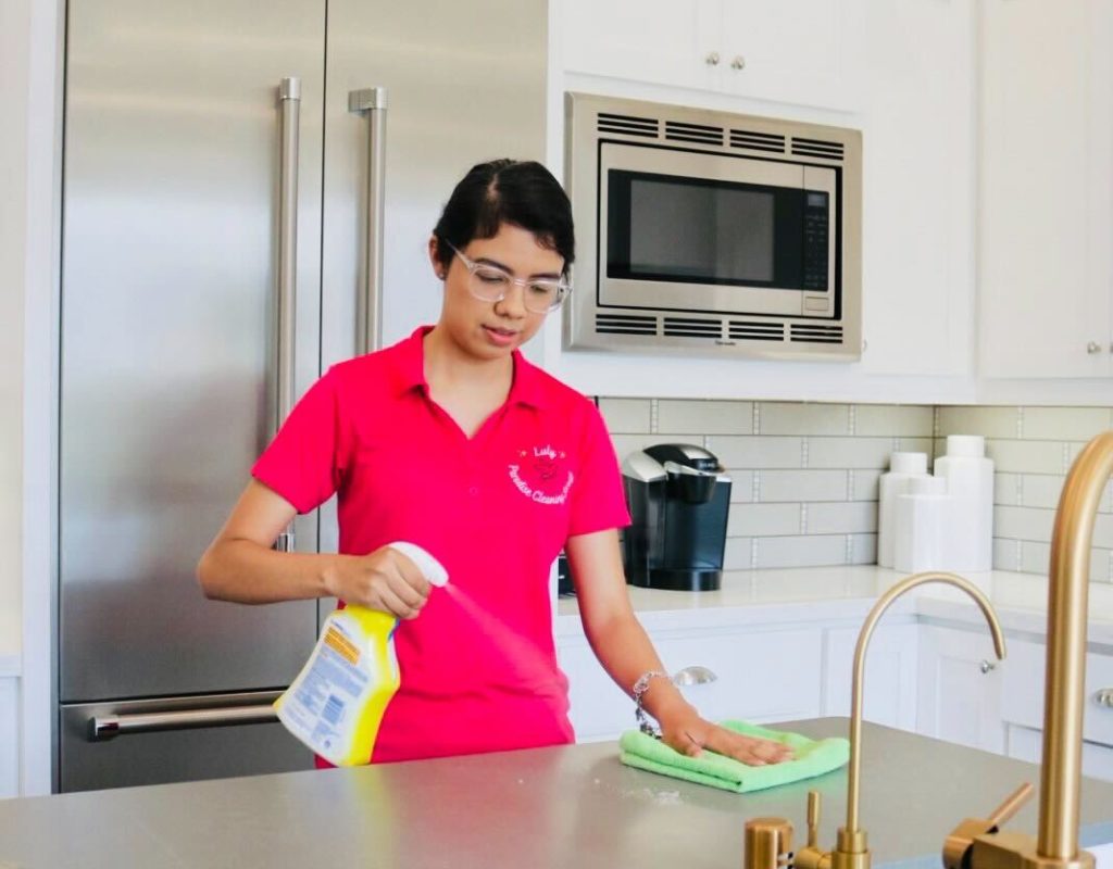 Professional cleaner wiping kitchen counters during scheduled cleaning service in Conroe